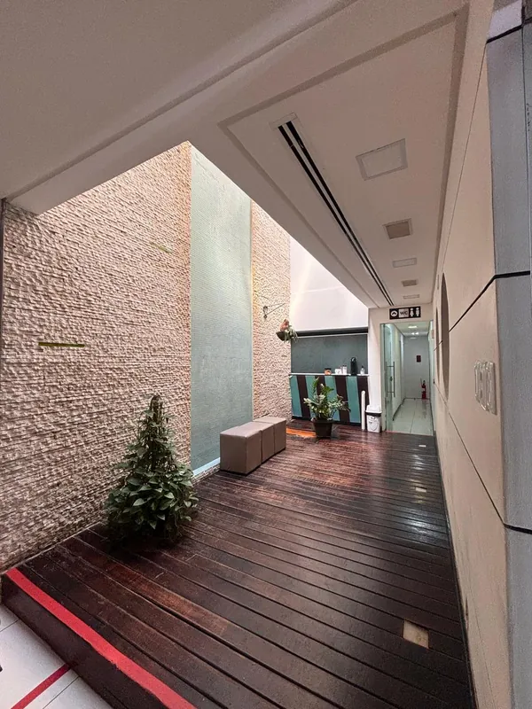 Ambiente interno moderno da Clínica Bixo's, com piso em madeira e parede de pedra